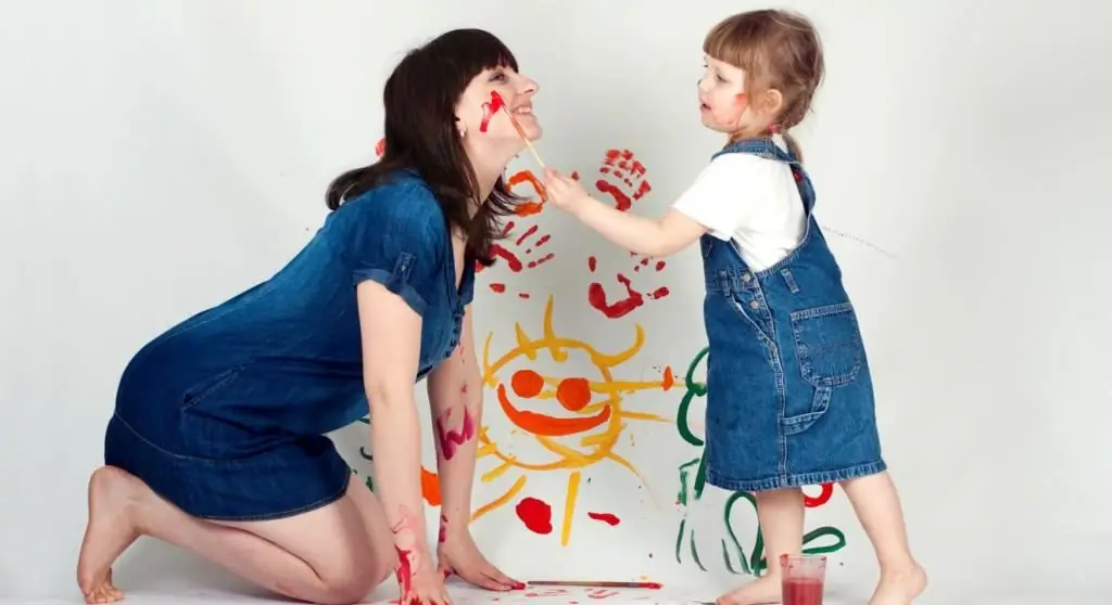 menina desenha na bochecha de sua mãe